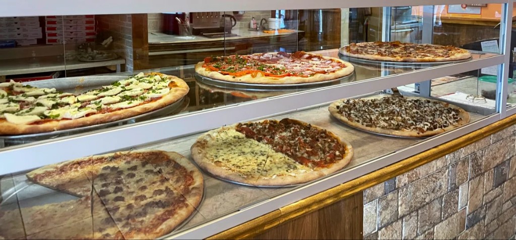 Fresh pizzas in the display case at Pecorino's Pizzeria